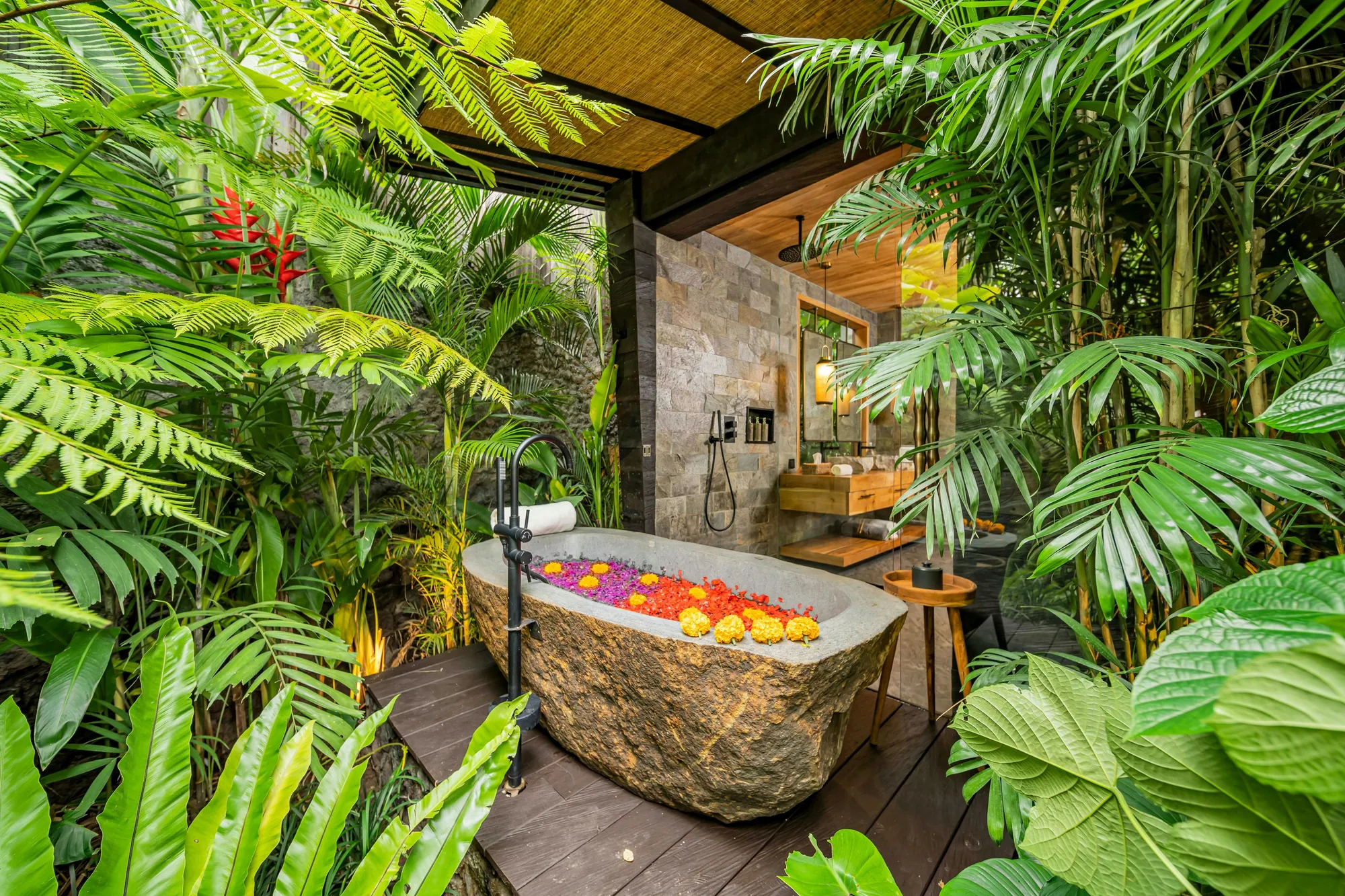 An open-air stone bath surrounded by tropical plants